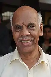Photograph of an old man in white shirt.