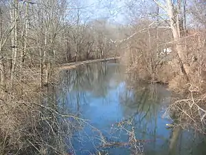 Leafless trees overhang a water channel that is uniformly about 25 feet (7.6 meters) wide.