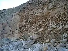 Above the current beach (rounded rocks) can be seen a layer of pebbles from about 120,000 years ago. Above them are head deposits, angular pieces from 100,000 to 20,000 years ago