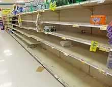 A supermarket aisle with a large section empty save for scattered packages of bottled water