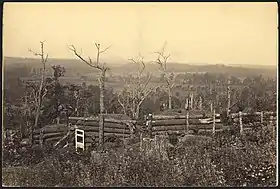 Sepia toned photo shows field fortifications built from logs.