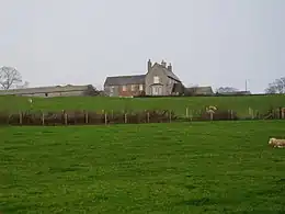 View across garden to fields. Small redbrick cottage to left.