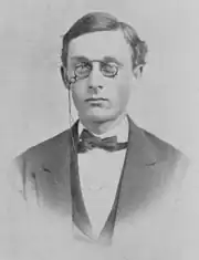 Bust photograph of Richards wearing a bowtie and eyeglasses with chain