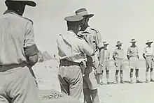 LIEUTENANT-GENERAL SIR LESLIE MORSHEAD, GENERAL-OFFICER COMMANDING A.I.F. (M.E.), PINNING THE RIBBON OF THE ORDER OF THE BRITISH EMPIRE ON LIEUTENANT COLONEL R.J.H. RISSON, COMMANDER ROYAL ENGINEERS, 9TH AUSTRALIAN DIVISION, AT A PARADE AT MAIN HEADQUARTERS OF THE DIVISION, location is North Africa: Western Desert, Western Desert (Egypt), El Alamein Area, El Alamein