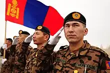 Mongolian soldiers salute while the Mongolian flag waves at the Transit Center at Manas, where they stayed for several days before moving forward to Afghanistan to support Operation Enduring Freedom.