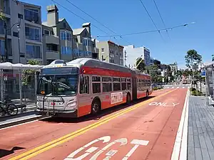 A bus stop with a trolleybus in the median of an urban arterial