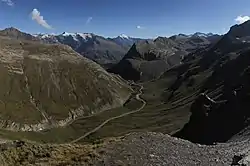 A view down to a mountain valley with a road parallel to a stream