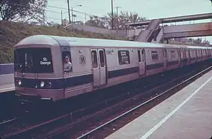 Train at a station, with its driver leaning out the window to pose for the camera