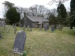A grassed graveyard in the foreground with a small one-storey chapel in the background
