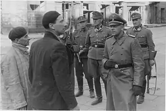 NARA copy #21, IPN copy #20Jewish traitorsStroop and Maximilian von Herff (likely) at Muranowski Square near Naleweki and Miła intersection with Nalewki 42 in the back. Possibly taken May 14, 1943