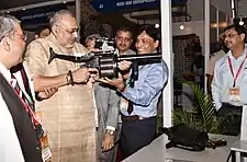 Minister holding a 40 mm Multi Grenade Launcher (MGL) and on the table the 38 mm Multi Shell Launcher both manufactured by OFT