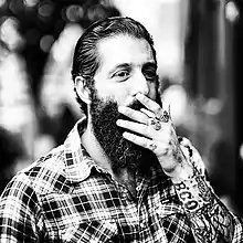 Image 30A man with sleeve tattoos, beard and flannel shirt, mid 2010s (from 2010s in fashion)